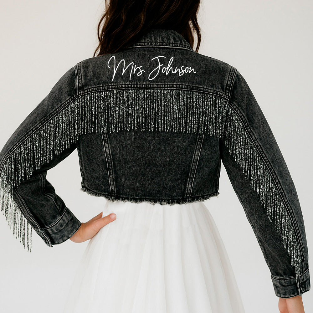 a woman wearing a jean jacket with fringes on it