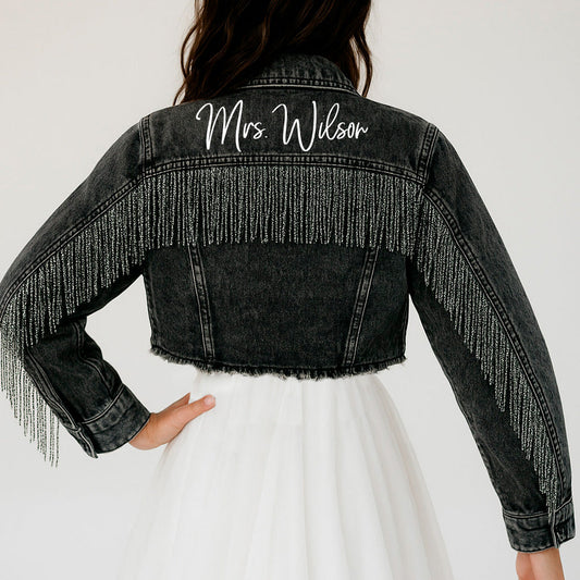 a woman wearing a jean jacket with fringes on it