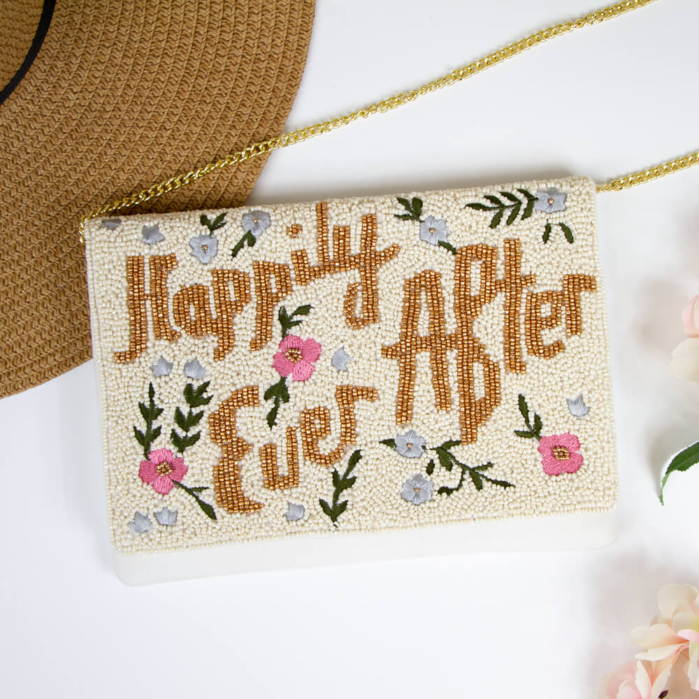 A beaded bridal clutch with 'Happily Ever After' text in gold, adorned with intricate floral patterns. Made from durable canvas, this 7 x 9.5 x 1 inch clutch showcases the unique charm of handmade items, ensuring no two are exactly alike. Ideal for holding wedding day essentials.