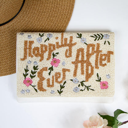 A beaded bridal clutch with 'Happily Ever After' text in gold, adorned with intricate floral patterns. Made from durable canvas, this 7 x 9.5 x 1 inch clutch showcases the unique charm of handmade items, ensuring no two are exactly alike. Ideal for holding wedding day essentials.