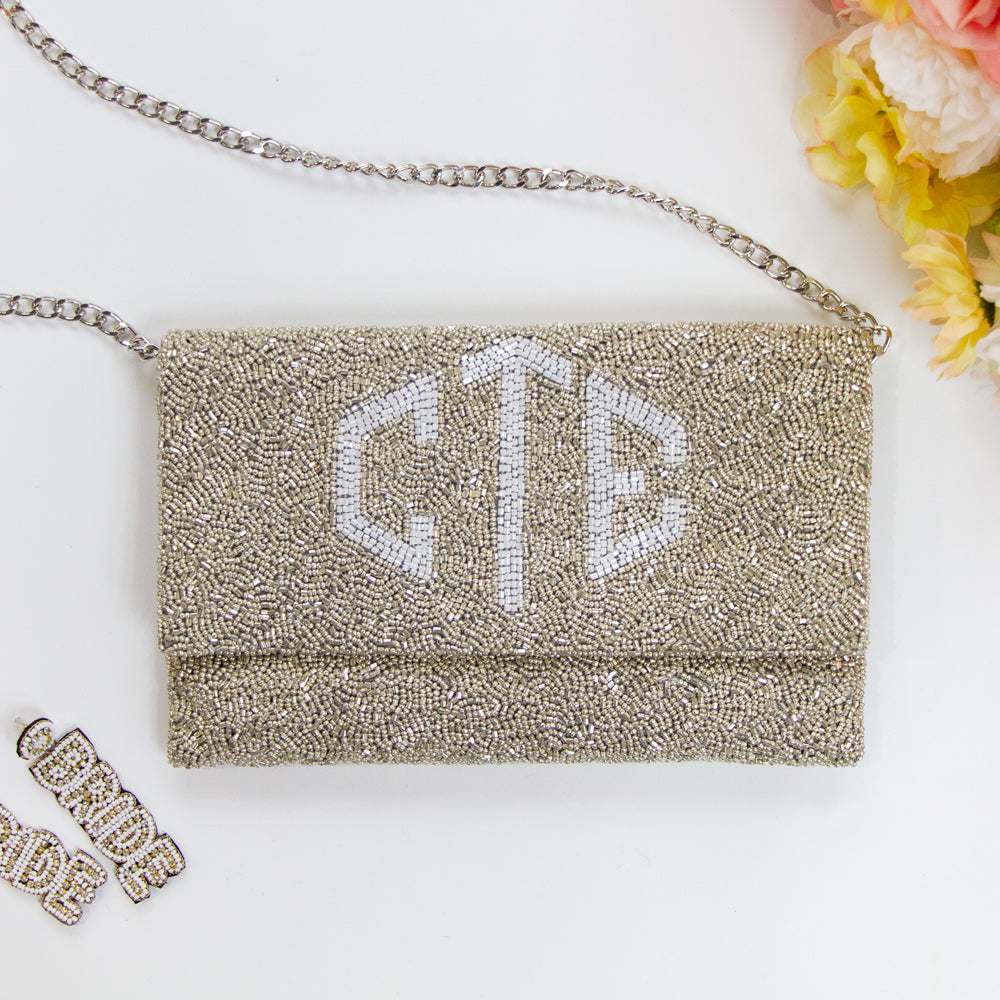 Exquisite Bridal Clutch: Custom Monogram Clutch Purse measuring 9 1/2″ wide x 5″ tall. Featuring rainbow clutch design with white text beading, complemented by a velvet interior. Each handmade clutch is unique, ideal for brides desiring a personalized touch on their special day.