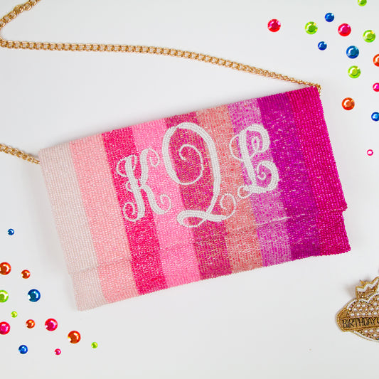 Exquisite Bridal Clutch: Custom Monogram Clutch Purse measuring 9 1/2″ wide x 5″ tall. Featuring rainbow clutch design with white text beading, complemented by a velvet interior. Each handmade clutch is unique, ideal for brides desiring a personalized touch on their special day.