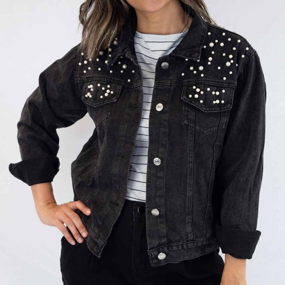 a woman wearing a black jean jacket with silver studs