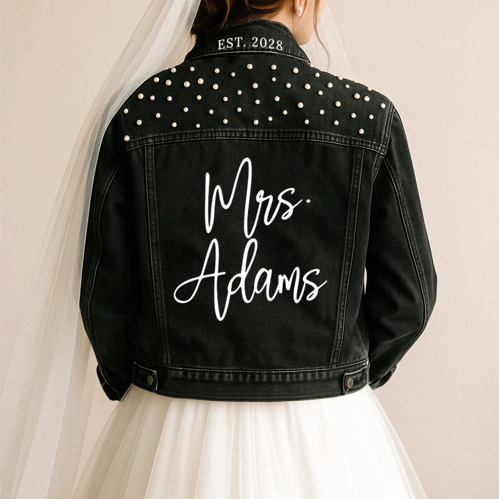 a bride wears a black jean jacket with the words mrs adams written on it