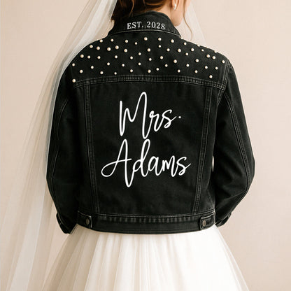 a bride wears a black jean jacket with the words mrs adams written on it
