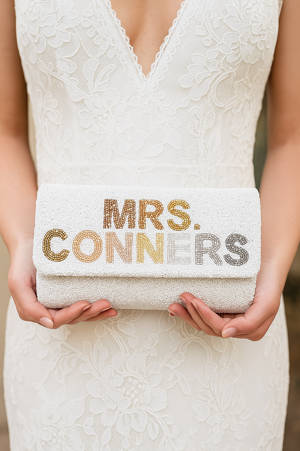A person is holding a white clutch purse with the text "Mrs. Conners" printed on it.