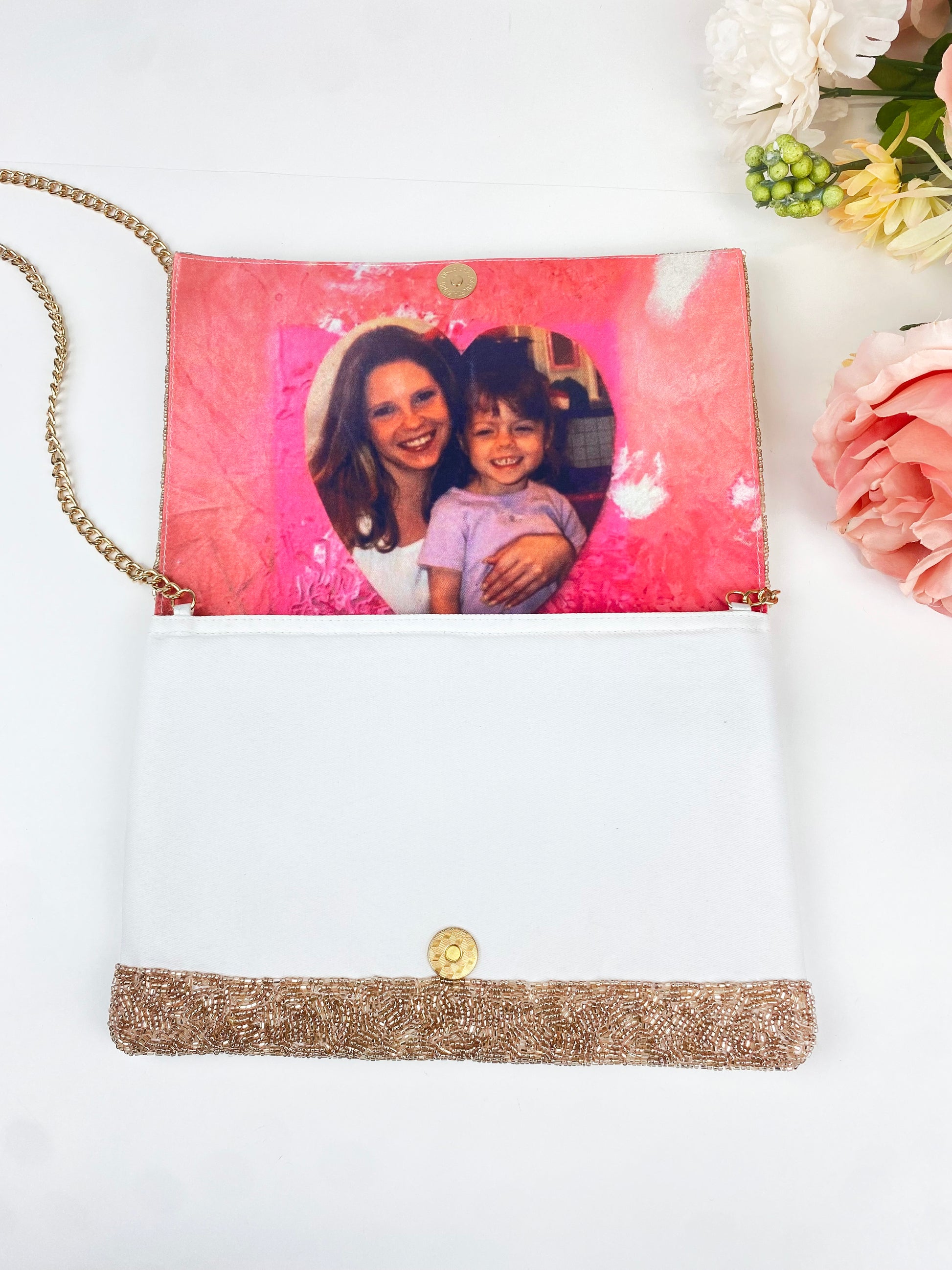 a pink and white handbag with a gold-colored clasp, and inside the bag is a photo of a woman and a child.