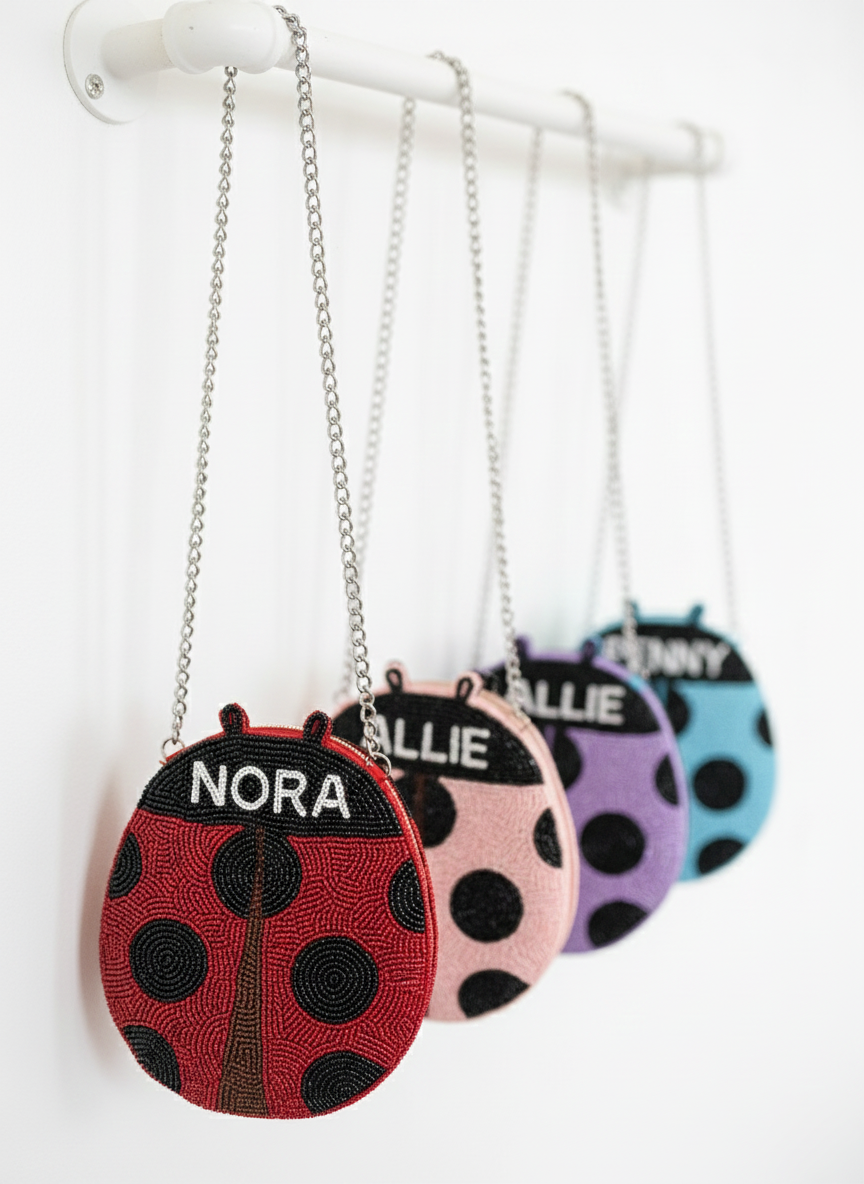 A row of colorful handbags with the name "Nora" printed on them, hanging from a white metal bar.