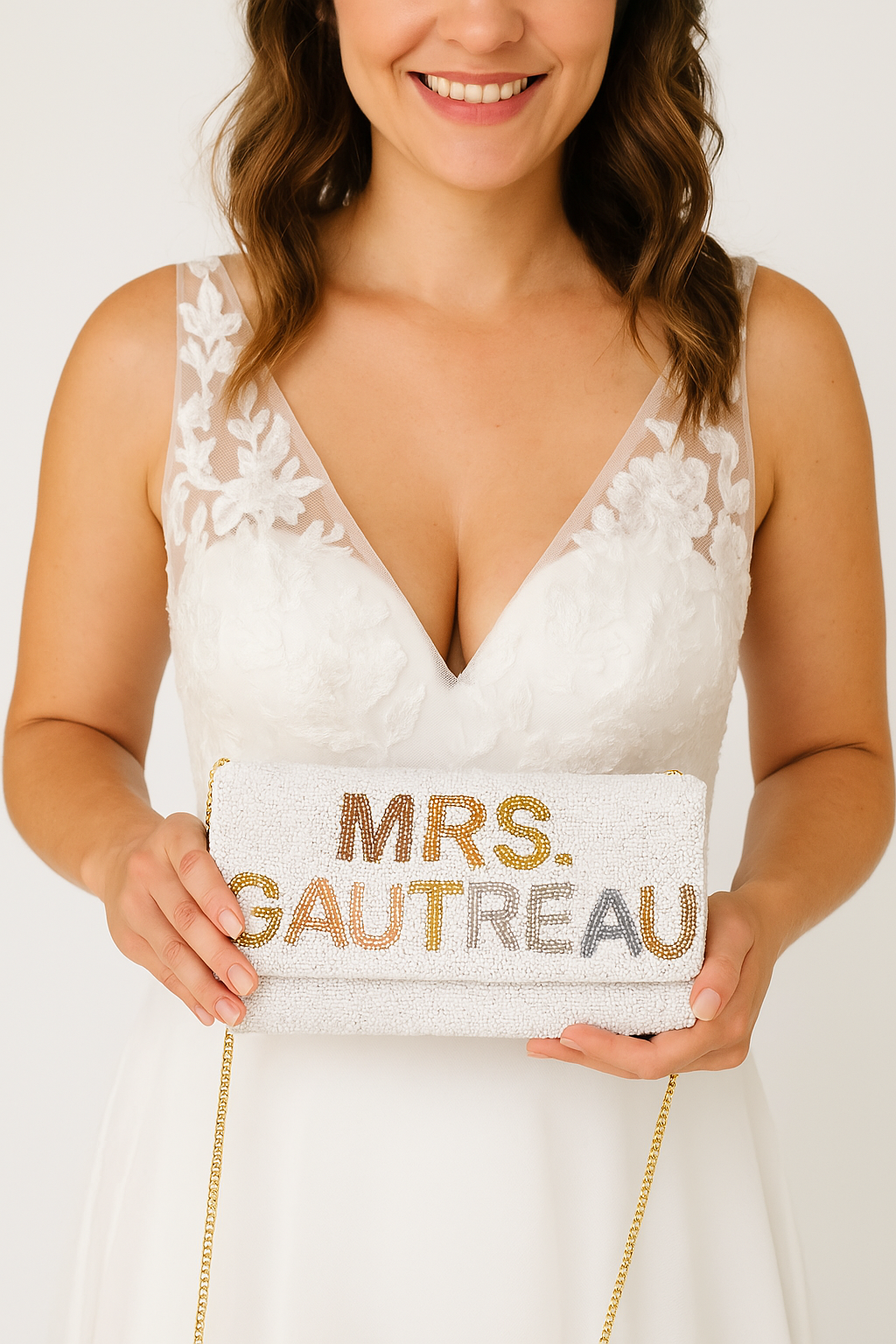 A woman in a white wedding dress holding a white clutch purse with the text "Mrs. Gautreau" printed on it.