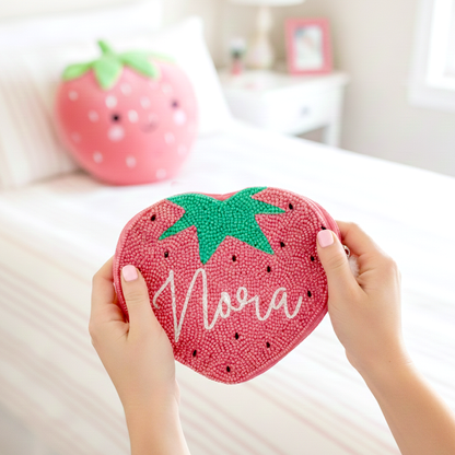 A person's hands holding a heart-shaped bag with a personalized name on it, in a bedroom setting.