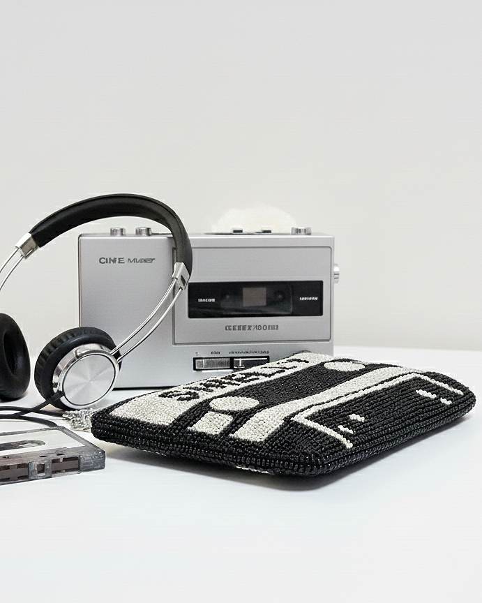 a silver cassette tape player, a pair of black headphones, and a black and white handbag with a crochet design.