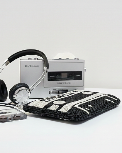 a silver cassette tape player, a pair of black headphones, and a black and white handbag with a crochet design.