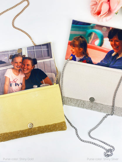 two purses, one yellow and one silver, with a chain attached to them. The purses are placed on a white surface, and there are two photographs attached to the purses, depicting a woman and a child.