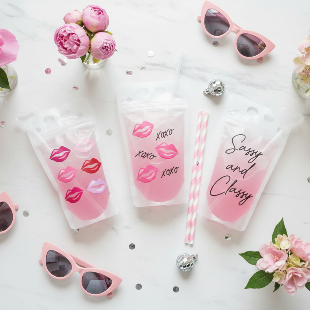 pink sunglasses, pink lip pouch drinks, and pink flowers arranged on a white marble surface.