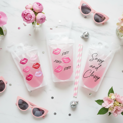 pink sunglasses, pink lip pouch drinks, and pink flowers arranged on a white marble surface.