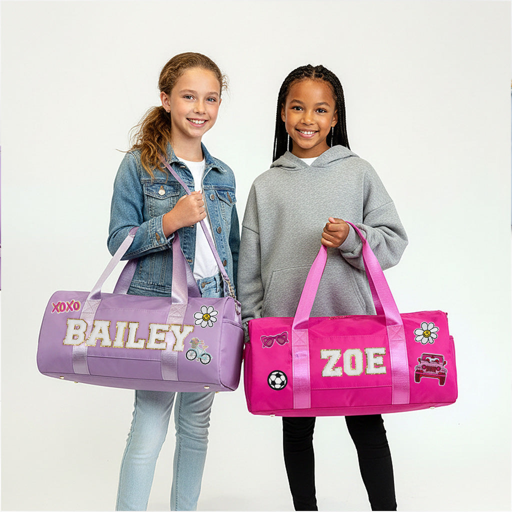 Two young girls are holding colorful duffle bags with personalized names on them.