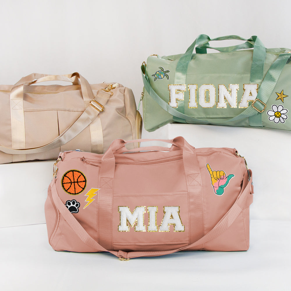 three colorful duffel bags with personalized names and various stickers or patches on them.