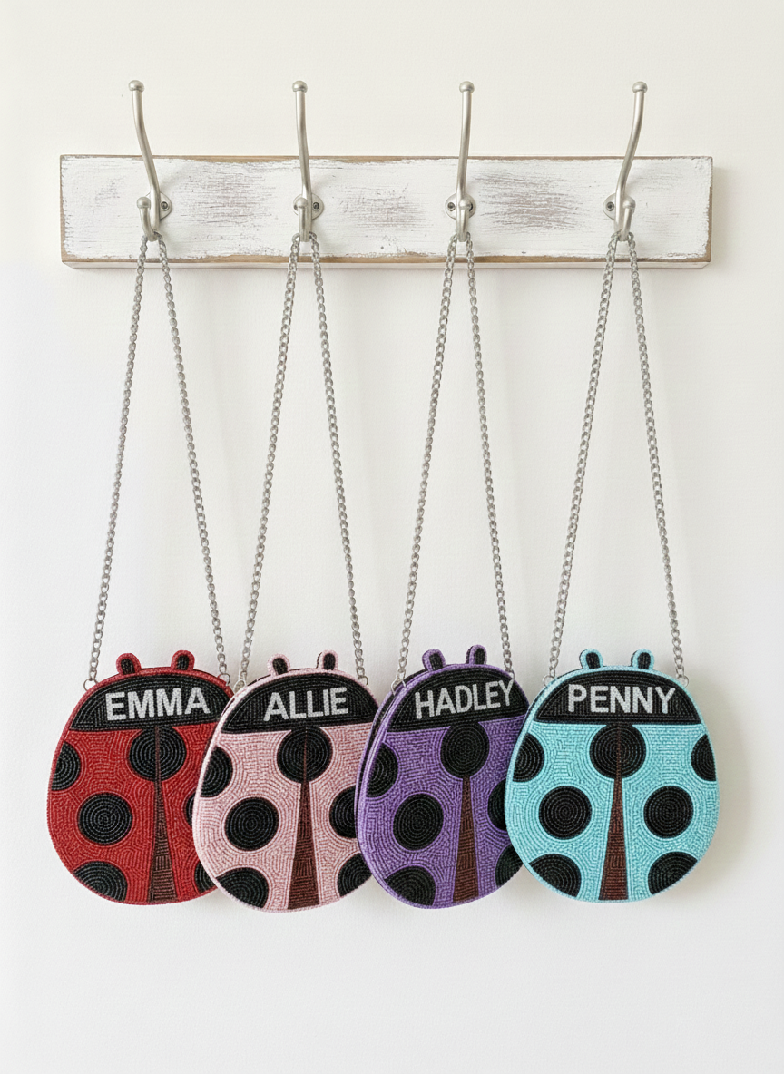 A row of four handbags with ladybug designs, each with a different name printed on it.