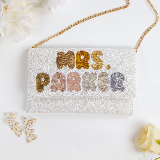 Handmade bridal clutch featuring bubble letters seed bead design, perfect for wedding day essentials. Elegant and unique addition for brides.