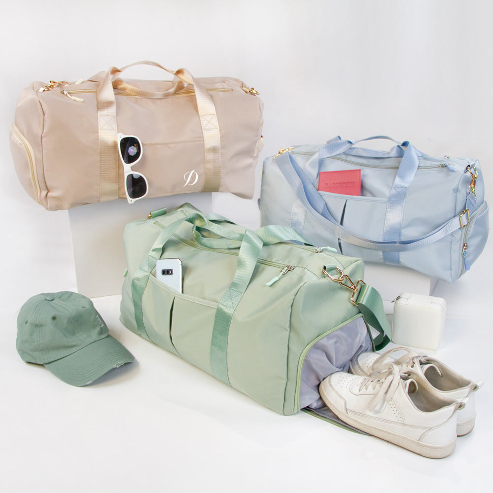 a collection of travel accessories, including three duffel bags in various colors, a hat, and a pair of sneakers.