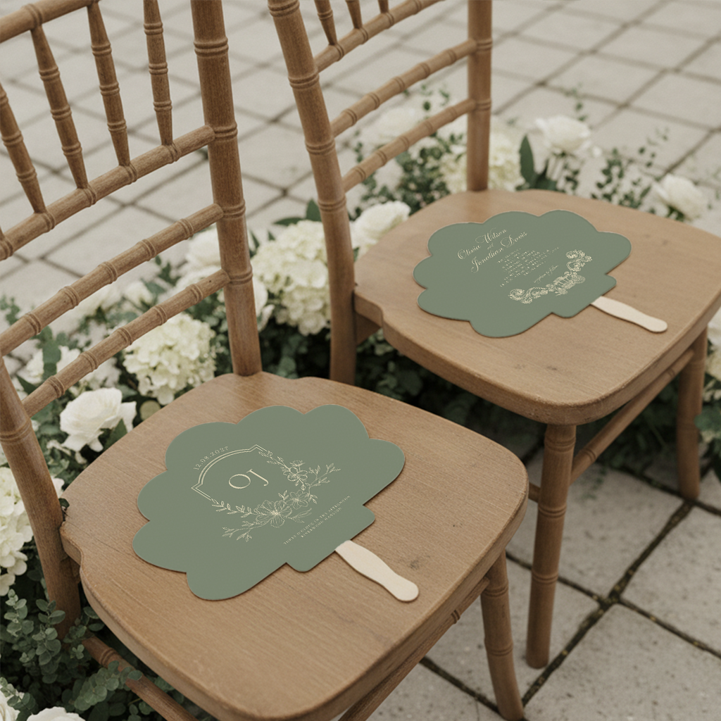 two wooden chairs with green fan-shaped cards placed on them, surrounded by white flowers.