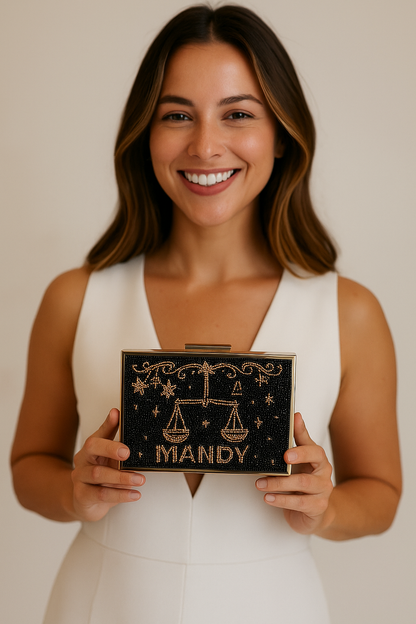 A woman in a white dress is smiling and holding a black clutch purse with the word "MIANDY" printed on it.