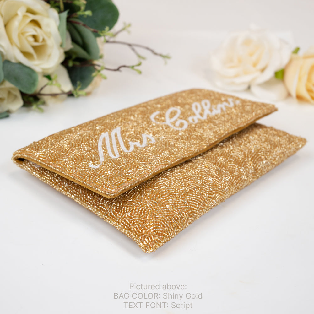 a pair of gold glittered clutches with a bouquet of flowers in the background
