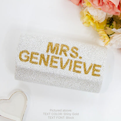 "Custom Mrs (Last Name)" beaded bridal clutch, intricately handmade for an elegant touch on the wedding day. Sized at 9.5in x 5in x 3in with an option for a gold or silver chain. Each bridal clutch boasts a unique character, highlighting the beauty of handcrafted items. Can be personalized with a custom date inside. An exquisite addition to any bridal ensemble or a thoughtful gift for soon-to-be brides.