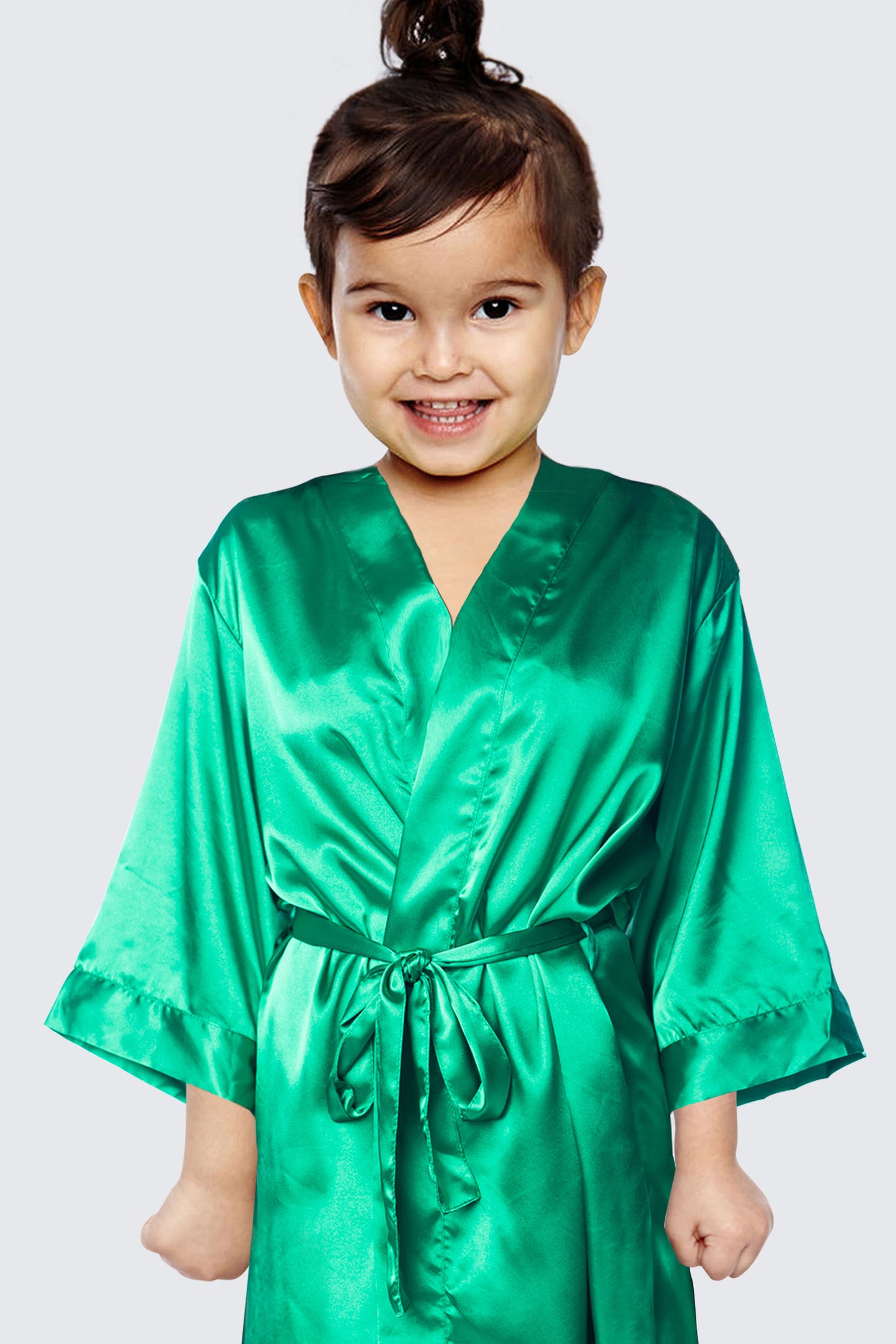 a little girl wearing a green robe and smiling