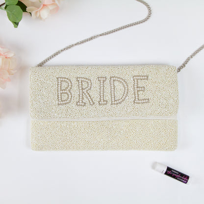 Elegant Bridal Clutch: White Bride Clutch Purse with gold text, measuring 10.5 x 6 x 1 in. Crafted from durable canvas with a magnetic snap closure. Each clutch is handmade, showcasing intricate beading patterns, ensuring a unique and special accessory for the bride on her big day