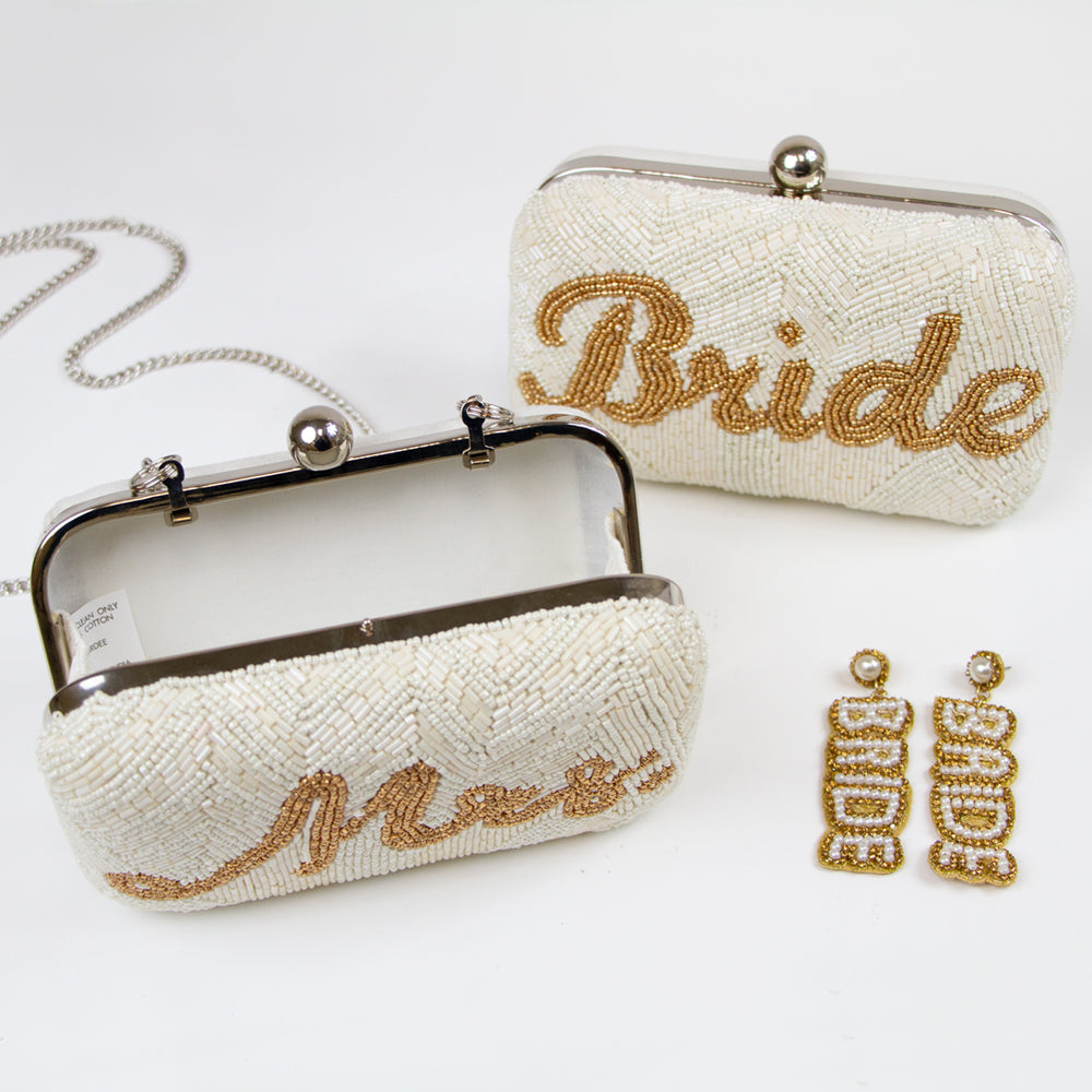 Elegantly handcrafted Bride, Mrs. Bridal Clutch in white with intricate gold text and beading. Perfect for a wedding day, this unique bridal clutch seamlessly blends functionality and style, holding all essentials with grace. A one-of-a-kind gift option for brides, showcasing the distinct beauty of artisanal craftsmanship.