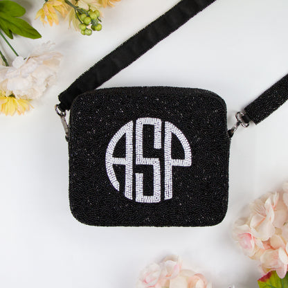 Customizable Monogram Crossbody Bag with beaded strap, ideal for summer and evening events. Features an 8x8 inch dimension, zipper closure, and a 46-inch detachable beaded strap. Each handcrafted piece boasts its unique color, texture, and bead pattern.