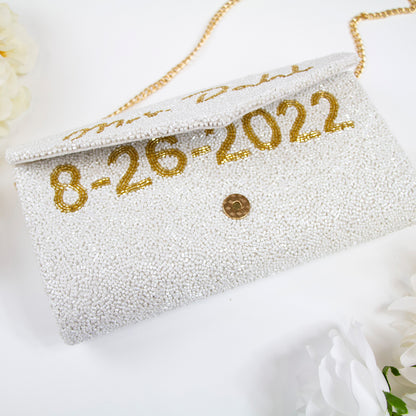 Handcrafted Custom Wedding Envelope Bridal Clutch (ENV) with intricate beading, perfect for the special wedding day. This 10" W x 6" H clutch, available with a gold or silver chain, elegantly complements any bridal ensemble. With the option for a custom date inside, it serves as a memorable keepsake or thoughtful gift, showcasing the unique charm of artisan-made accessories.