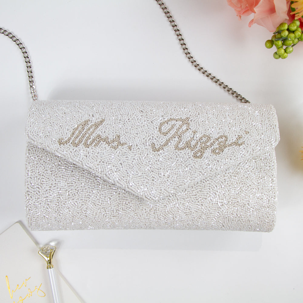 Handcrafted Custom Wedding Envelope Bridal Clutch (ENV) with intricate beading, perfect for the special wedding day. This 10" W x 6" H clutch, available with a gold or silver chain, elegantly complements any bridal ensemble. With the option for a custom date inside, it serves as a memorable keepsake or thoughtful gift, showcasing the unique charm of artisan-made accessories.