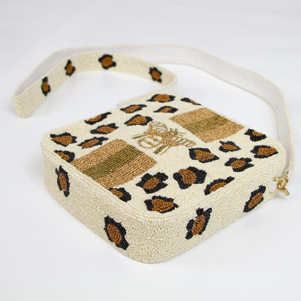 Alt Text: "Trendy Leopard Print Beaded Box Bag, blending a vibrant leopard print with playful pink lightning bolt accents on the crossbody strap. This 8x8x2-inch handcrafted purse features a peach canvas back, enhanced by chic gold details. The detachable 46-inch beaded strap offers versatility for any occasion. Each bag is uniquely crafted, ensuring a distinct and exclusive accessory to complement both day and night looks