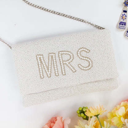 Elegant white MRS Bridal Clutch, handcrafted with intricate beading and a distinctive pattern. Made from durable canvas with a satin finish inside and secured with a magnetic snap closure. Measuring 10 x 6 x 1 inches, this bridal clutch is perfect for holding wedding day essentials and showcases the unique charm and variations of handmade items.