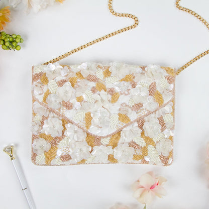 Exquisite floral beaded clutch, intricately handcrafted with floral and leaf patterns, perfect for brides or bridesmaids. Features gold chain, magnetic snap closure, and dimensions of 10in x 7in x 1.5in. Each clutch showcases unique craftsmanship and is ideal for storing wedding day essentials.