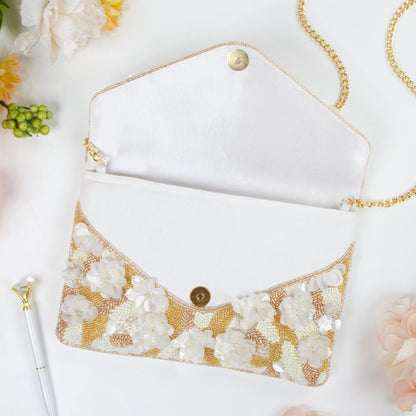 Exquisite floral beaded clutch, intricately handcrafted with floral and leaf patterns, perfect for brides or bridesmaids. Features gold chain, magnetic snap closure, and dimensions of 10in x 7in x 1.5in. Each clutch showcases unique craftsmanship and is ideal for storing wedding day essentials.