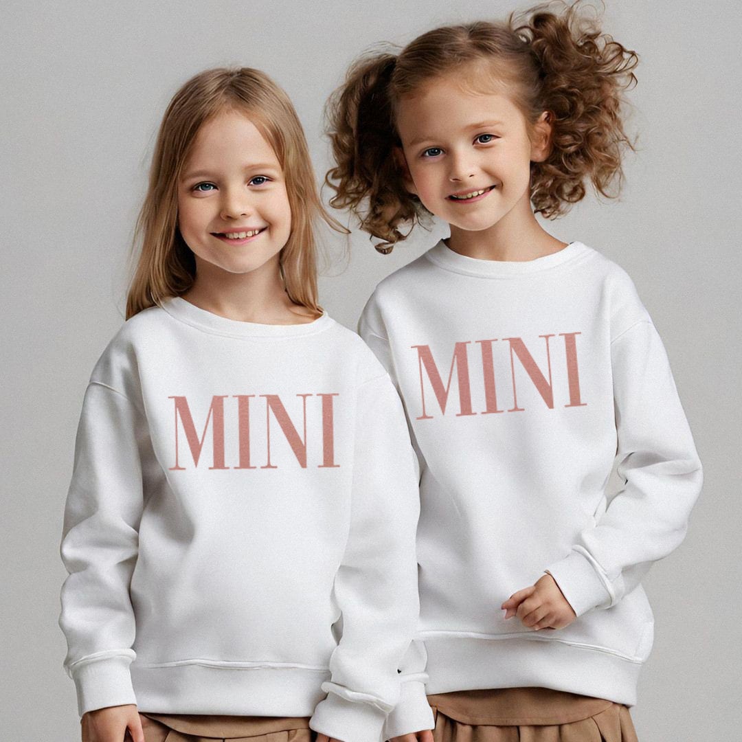 two young girls wearing white sweatshirts with the word mini printed on them