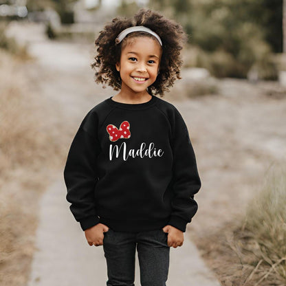 a little girl wearing a bow sweatshirt